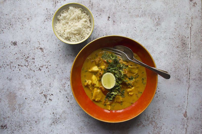 Katsu-Fischcurry mit weissen Fischstücken, Reis, frischem Koriander und Limettenschnitzen