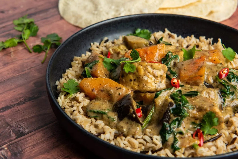 Veganes Massaman Curry mit Butternut, Tempeh, Aubergine und Spinat, garniert mit Chili und Koriander