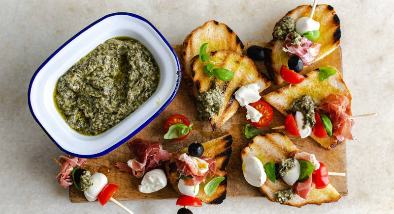 Caprese-Spiesse mit Mozzarella, Cherry-Tomaten, Prosciutto und Oliven, dazu Basilikumpesto