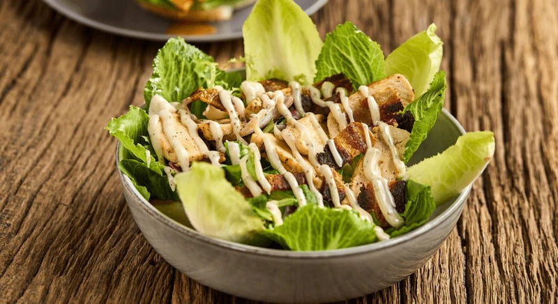 Caesar Salad mit Pouletstreifen, Speckwürfeln, Parmesan und Croutons auf Römersalat