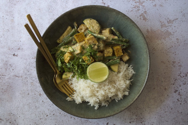 Grünes Thai-Curry mit Tofuwürfeln, grünen Bohnen und Zucchini auf Basmatireis, mit Koriander und Limette