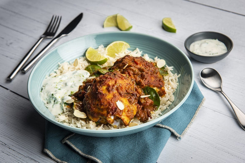 Im Ofen gebackene Jalfrezi-Pouletschenkel mit Spinat, Kokosjoghurt, gerösteten Mandelblättchen und Koriander