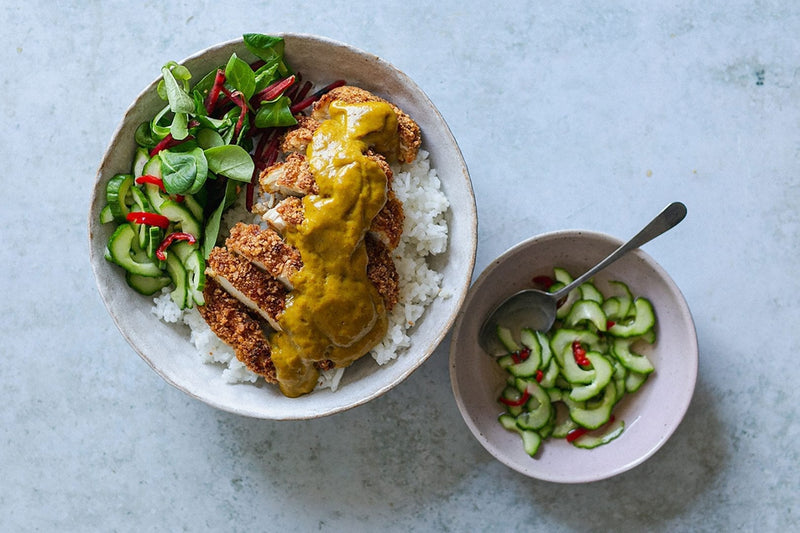 Paniertes Poulet in Streifen auf Reis mit Katsu-Currysauce und eingelegten Gurkenscheiben