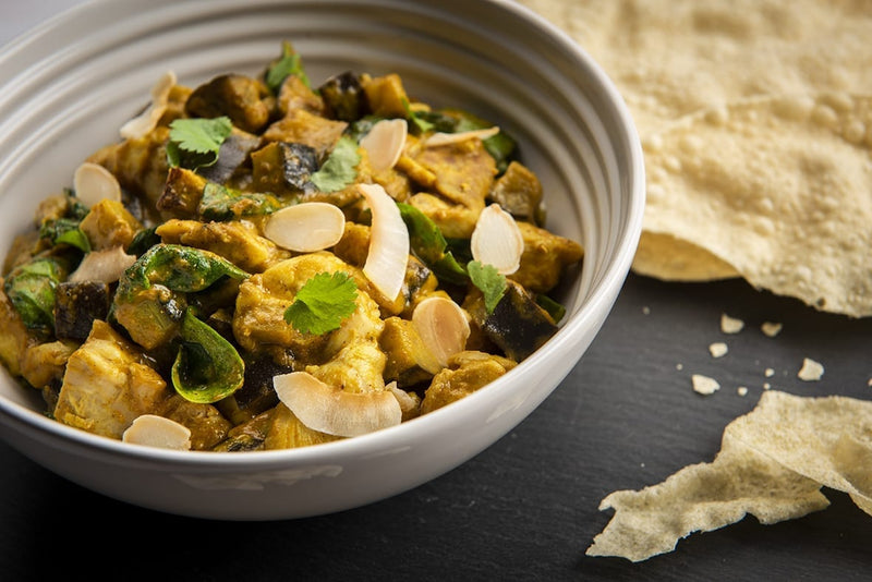 Mildes Korma mit Poulet, Aubergine und Spinat, bestreut mit Mandeln und Kokosflocken
