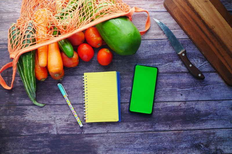Smartphone, Notizblock und Gemüse auf dem Küchentisch: die Monash FODMAP App im Alltag