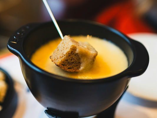 Käsefondue low FODMAP: Brotwürfel mit geschmolzenem Käse im Caquelon