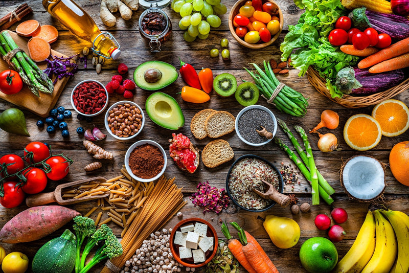 Bunte Lebensmittel von oben fotografiert: Gemüse, Obst, Nüsse, Hülsenfrüchte und Getreide