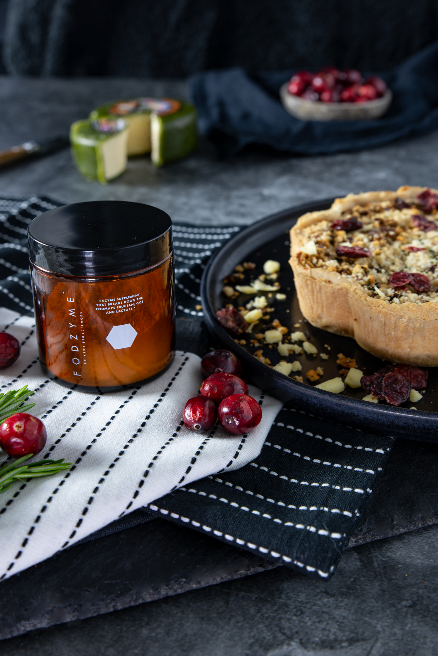 Ein Fodzyme-Glas neben Cranberries und einer Beeren-Nuss-Tarte.